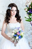 Belle jeune mariée avec des fleurs nous regardant heureusement images stock Belle jeune mariée avec des fleurs nous regardant heureusement images stock