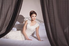Belle jeune jeune mariée avec la coiffure de maquillage et de fantaisie dans la séance costumée sur le lit image stock Belle jeune jeune mariée avec la coiffure de maquillage et de fantaisie dans la séance costumée sur le lit image stock