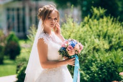 Belle jeune mariée mince posant contre la verdure en parc Elle est habillée dans une belle robe de mariage blanche, dedans photo libre de droits Belle jeune mariée mince posant contre la verdure en parc Elle est habillée dans une belle robe de mariage blanche, dedans photo libre de droits