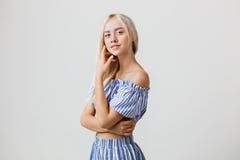 Belle la fille blonde calme et amicale dans l'équipement d'été est pose de sourire à la caméra, au-dessus du fond blanc émotions photo stock Belle la fille blonde calme et amicale dans l'équipement d'été est pose de sourire à la caméra, au-dessus du fond blanc émotions photo stock
