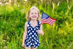 Belle petite fille avec de longs cheveux blonds bouclés avec le drapeau américain images stock Belle petite fille avec de longs cheveux blonds bouclés avec le drapeau américain images stock