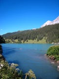 Belle vue au-dessus d'un lac suisse bleu avec les montagnes et les fleurs couvertes de neige images stock Belle vue au-dessus d'un lac suisse bleu avec les montagnes et les fleurs couvertes de neige images stock