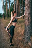 Bello atleta della donna, foresta dello smartphone delle cuffie della ragazza, lista musicale radiofonica di riscaldamento di mus fotografia stock Bello atleta della donna, foresta dello smartphone delle cuffie della ragazza, lista musicale radiofonica di riscaldamento di mus fotografia stock
