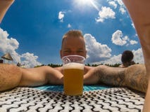 Bello giovane che gode della birra allo stagno fotografia stock Bello giovane che gode della birra allo stagno fotografia stock