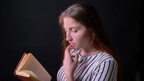 Bello libro di lettura pensieroso della giovane donna e pensare, vista di profilo, isolata su fondo nero archivi video Bello libro di lettura pensieroso della giovane donna e pensare, vista di profilo, isolata su fondo nero archivi video
