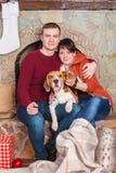 Bello portrain di giovane famiglia con il cane sveglio del cane da lepre la vigilia del nuovo anno fotografia stock Bello portrain di giovane famiglia con il cane sveglio del cane da lepre la vigilia del nuovo anno fotografia stock