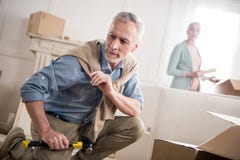 Bemannen Sie auf Boden mit Hammer mit Frau hinten in der Hand sitzen Lizenzfreie Stockfotografie Bemannen Sie auf Boden mit Hammer mit Frau hinten in der Hand sitzen Lizenzfreie Stockfotografie