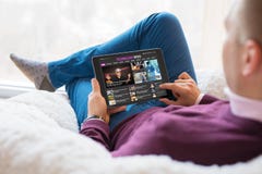Bemannen Sie Lesetechnologienachrichten auf Tablette beim zu Hause sitzen lizenzfreie stockbilder Bemannen Sie Lesetechnologienachrichten auf Tablette beim zu Hause sitzen lizenzfreie stockbilder