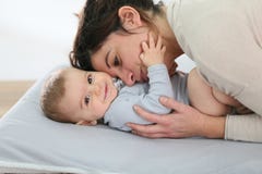 Bemuttern Sie und ihr Baby, das auf einer ändernden Tabelle cudling ist Lizenzfreie Stockfotos Bemuttern Sie und ihr Baby, das auf einer ändernden Tabelle cudling ist Lizenzfreie Stockfotos