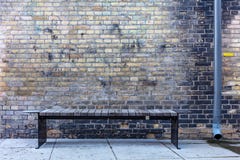 Bench and a rain pipe in a dark corner royalty free stock photography Bench and a rain pipe in a dark corner royalty free stock photography