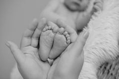 Benen van de pasgeboren baby in de handen van de moeder royalty-vrije stock afbeelding Benen van de pasgeboren baby in de handen van de moeder royalty-vrije stock afbeelding