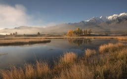 Berg sjö i morgonmisten på bakgrunden av snöig berg och blå himmel royaltyfri fotografi Berg sjö i morgonmisten på bakgrunden av snöig berg och blå himmel royaltyfri fotografi