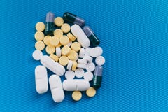 Berget av preventivpillerar Fördjupning beriberi Kulör läkarbehandling på en blå bakgrund arkivfoto Berget av preventivpillerar Fördjupning beriberi Kulör läkarbehandling på en blå bakgrund arkivfoto