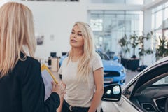 Berufsautohändler, der ihrem weiblichen Kunden hilft stockfotografie Berufsautohändler, der ihrem weiblichen Kunden hilft stockfotografie