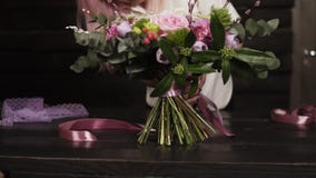 Berufsmädchenflorist bindet die Unterseite des Blumenstraußes mit silk rosa Bändern Dunkles Studio Langsame Bewegung stock video Berufsmädchenflorist bindet die Unterseite des Blumenstraußes mit silk rosa Bändern Dunkles Studio Langsame Bewegung stock video