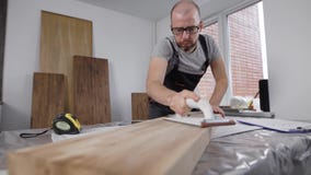 Berufstischler, der sorgfältig mit Seiten des hölzernen Brettes arbeitet stock footage Berufstischler, der sorgfältig mit Seiten des hölzernen Brettes arbeitet stock footage