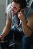 Best song for his training. Young handsome man in headphones using his smart phone and listening to music. Young man taking a break after his workout and royalty free stock images Best song for his training. Young handsome man in headphones using his smart phone and listening to music. Young man taking a break after his workout and royalty free stock images