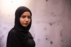 Beunruhigte attraktive moslemische Frau in einem schwarzen hijab mit einer grungy sch?digenden Wand im Hintergrund lizenzfreies stockfoto Beunruhigte attraktive moslemische Frau in einem schwarzen hijab mit einer grungy sch?digenden Wand im Hintergrund lizenzfreies stockfoto