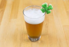 Bevanda della birra di giorno del ` s di St Patrick in un vetro trasparente con un'alta schiuma bianca ed in trifoglio su una bas fotografie stock Bevanda della birra di giorno del ` s di St Patrick in un vetro trasparente con un'alta schiuma bianca ed in trifoglio su una bas fotografie stock