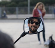 Bezinning van de mens met glazen en baard die in een motorspiegel glimlachen stock afbeelding Bezinning van de mens met glazen en baard die in een motorspiegel glimlachen stock afbeelding