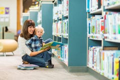 Biblioteca feliz de Reading Book In do menino e do professor imagens de stock royalty free Biblioteca feliz de Reading Book In do menino e do professor imagens de stock royalty free