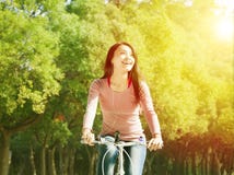 Bicicleta asiática bonita da equitação da jovem mulher no parque fotografia de stock Bicicleta asiática bonita da equitação da jovem mulher no parque fotografia de stock