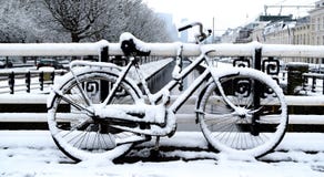 Bicicletta parcheggiata un giorno di inverno nella città immagine stock libera da diritti Bicicletta parcheggiata un giorno di inverno nella città immagine stock libera da diritti