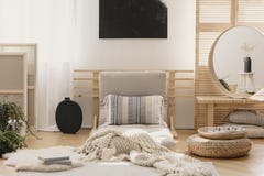 Biel ciepła koc i wzorzysta poduszka na beżowym futon w eleganckim naturalnym sypialni wnętrzu z eleganckim round lustrem w drewn obrazy stock Biel ciepła koc i wzorzysta poduszka na beżowym futon w eleganckim naturalnym sypialni wnętrzu z eleganckim round lustrem w drewn obrazy stock