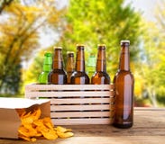 Bierflaschen und Kartoffelchips auf Holztisch mit unscharfem Park auf Hintergrund, farbiger Flasche, Nahrung und Getränkkonzept, lizenzfreies stockbild Bierflaschen und Kartoffelchips auf Holztisch mit unscharfem Park auf Hintergrund, farbiger Flasche, Nahrung und Getränkkonzept, lizenzfreies stockbild
