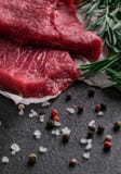 Bife cru com ramos dos alecrins no papel de pergaminho com pimenta e sal fotos de stock Bife cru com ramos dos alecrins no papel de pergaminho com pimenta e sal fotos de stock