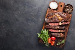 Bife, ervas e especiarias grelhados do ribeye em um fundo de pedra escuro Vista superior com espaço da cópia para seu texto fotografia de stock Bife, ervas e especiarias grelhados do ribeye em um fundo de pedra escuro Vista superior com espaço da cópia para seu texto fotografia de stock