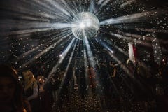 A big disco ball is hanging from the ceiling. A lot of people are dancing on the background royalty free stock photography A big disco ball is hanging from the ceiling. A lot of people are dancing on the background royalty free stock photography