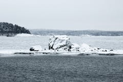 A big snowy rock on a partly frozen sea
