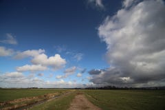 Big white and grey clouds and blue sky in wide angle view over the meadows of the Zuidplaspolder. In the Netherlands Royalty Free Stock Photo Big white and grey clouds and blue sky in wide angle view over the meadows of the Zuidplaspolder. In the Netherlands Royalty Free Stock Photo