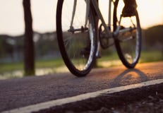 Bike at the summer sunset on road in city park. Cycle closeup wheel on blurred light at summer. stock photo Bike at the summer sunset on road in city park. Cycle closeup wheel on blurred light at summer. stock photo