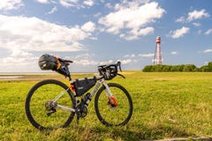 bikepacking at the north sea, view on the lighthouse of campen near emden with a packed gravel bike in front, north sea, germany