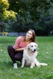 Bild av flickan som kramar hunden på grön gräsmatta fotografering för bildbyråer Bild av flickan som kramar hunden på grön gräsmatta fotografering för bildbyråer