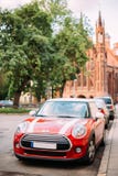Bilen för röd färg med vit gör randig på Mini Cooper Parked On Street royaltyfri fotografi Bilen för röd färg med vit gör randig på Mini Cooper Parked On Street royaltyfri fotografi