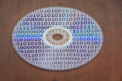 Binary code reflected in a compact disk surface against the background of wooden a background stock photos Binary code reflected in a compact disk surface against the background of wooden a background stock photos