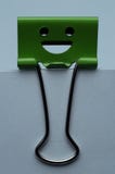 Green binder clip isolated on white papers, happiness character. stock photography Green binder clip isolated on white papers, happiness character. stock photography