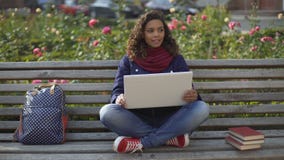 Biracial student in elevated mood sitting on bench, dreaming about bright future