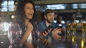 Biracialmeisje die in bar succesvolle weddenschap op sporten vieren, online bookmaker app stock video Biracialmeisje die in bar succesvolle weddenschap op sporten vieren, online bookmaker app stock video