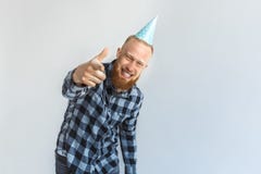 Birthday Concept. Mature man in cap standing on grey pointing at camera cheerful close-up stock photos Birthday Concept. Mature man in cap standing on grey pointing at camera cheerful close-up stock photos