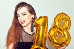 A birthday girl on her 18th birthday with gold number baloons. Excited eighteen girl with green make up and black dress smile. stock photo A birthday girl on her 18th birthday with gold number baloons. Excited eighteen girl with green make up and black dress smile. stock photo