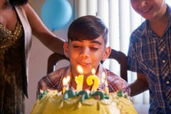 Birthday Party With Happy Latino Boy Blowing Candles On Cake royalty free stock photo Birthday Party With Happy Latino Boy Blowing Candles On Cake royalty free stock photo