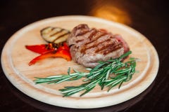 Bistecca della carne su un piatto di legno con un piatto laterale delle verdure arrostite fotografia stock Bistecca della carne su un piatto di legno con un piatto laterale delle verdure arrostite fotografia stock