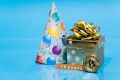 Bitcoin aniversario de 10 años, moneda con el sombrero de oro del presente del cumpleaños y del cumpleaños detrás de él y 10 años fotografía de archivo Bitcoin aniversario de 10 años, moneda con el sombrero de oro del presente del cumpleaños y del cumpleaños detrás de él y 10 años fotografía de archivo