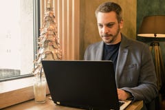 Biznesmen pracuje na jego laptopie przy kawiarnią Bożenarodzeniowy decorat zdjęcie stock Biznesmen pracuje na jego laptopie przy kawiarnią Bożenarodzeniowy decorat zdjęcie stock
