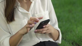 Biznesowa kobieta sprawdza jej telefonu obsiadanie pod drzewem w parku zdjęcie wideo Biznesowa kobieta sprawdza jej telefonu obsiadanie pod drzewem w parku zdjęcie wideo