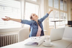 Bizneswoman z rękami szeroko rozpościerać podczas gdy siedzący przy biurem Obraz Stock Bizneswoman z rękami szeroko rozpościerać podczas gdy siedzący przy biurem Obraz Stock